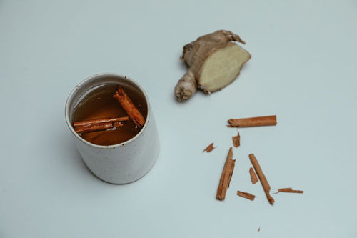 Cinnamon sticks and fresh ginger with a cup of tea